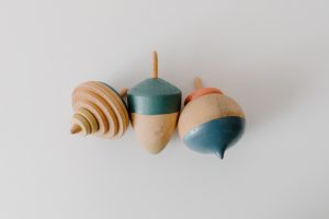 Toupies en bois traditionnelles poses sur une surface claire, illustrant les jouets en bois traditionnels comme la toupie, le bilboquet et le yoyo