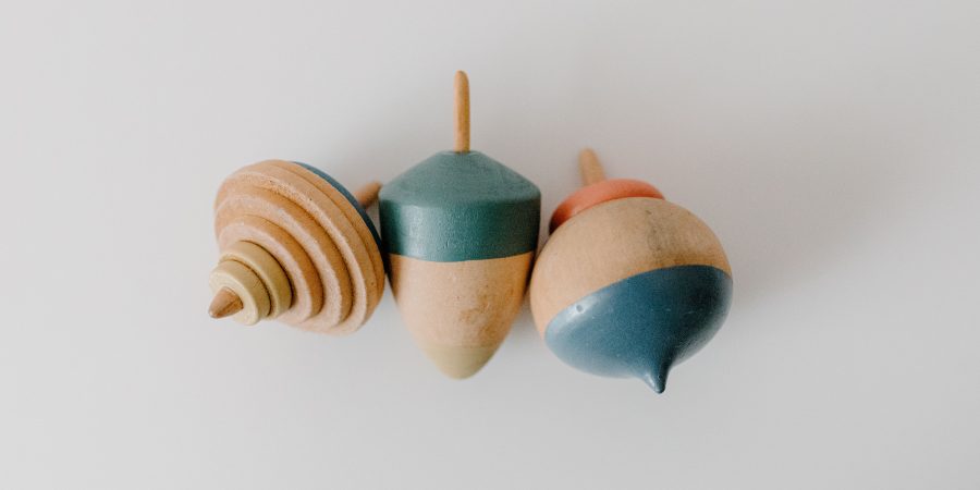 Toupies en bois traditionnelles poses sur une surface claire, illustrant les jouets en bois traditionnels comme la toupie, le bilboquet et le yoyo