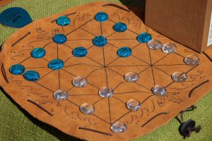 Plateau du moulin avec diagonales sur un tapis en cuir, avec des pions en verre bleus et transparents