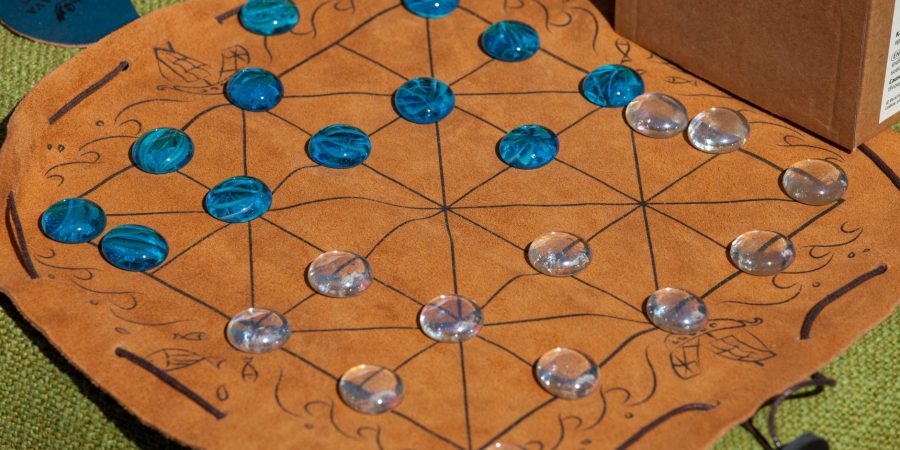 Plateau du moulin avec diagonales sur un tapis en cuir, avec des pions en verre bleus et transparents