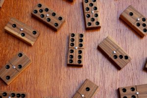 Dominos en bois à points noirs incrustés et rivet métallique central, éparpillés sur une table en bois