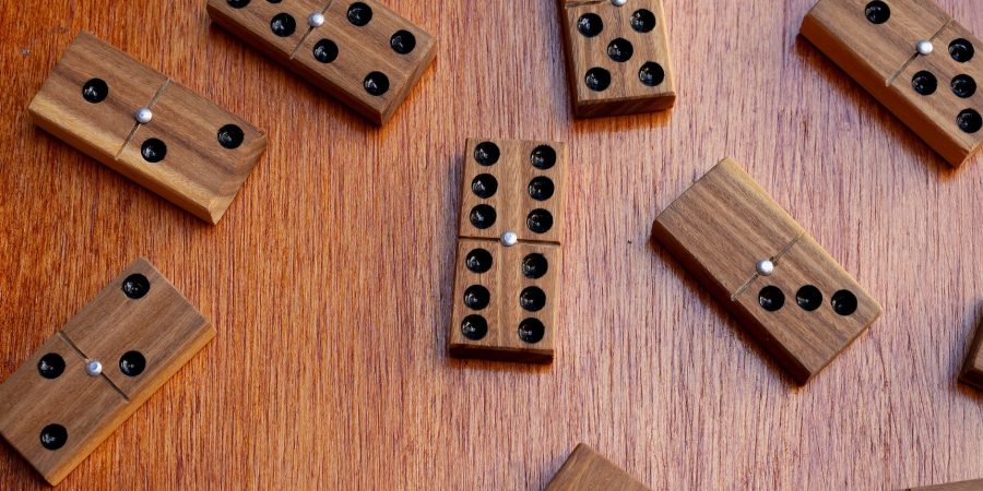 Dominos en bois à points noirs incrustés et rivet métallique central, éparpillés sur une table en bois