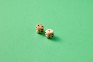 Deux dés en bois clair à points noirs sur un fond vert