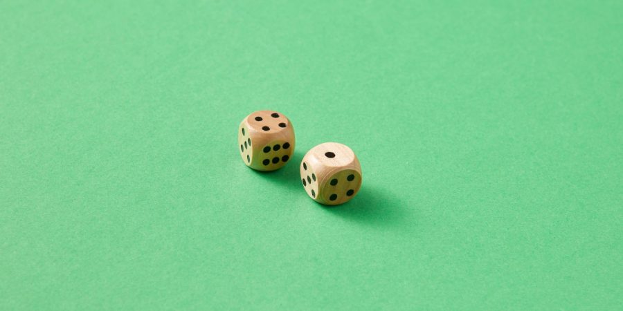 Deux dés en bois clair à points noirs sur un fond vert